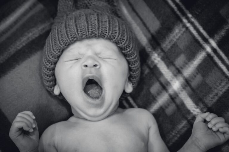 a baby yawning with a knit hat