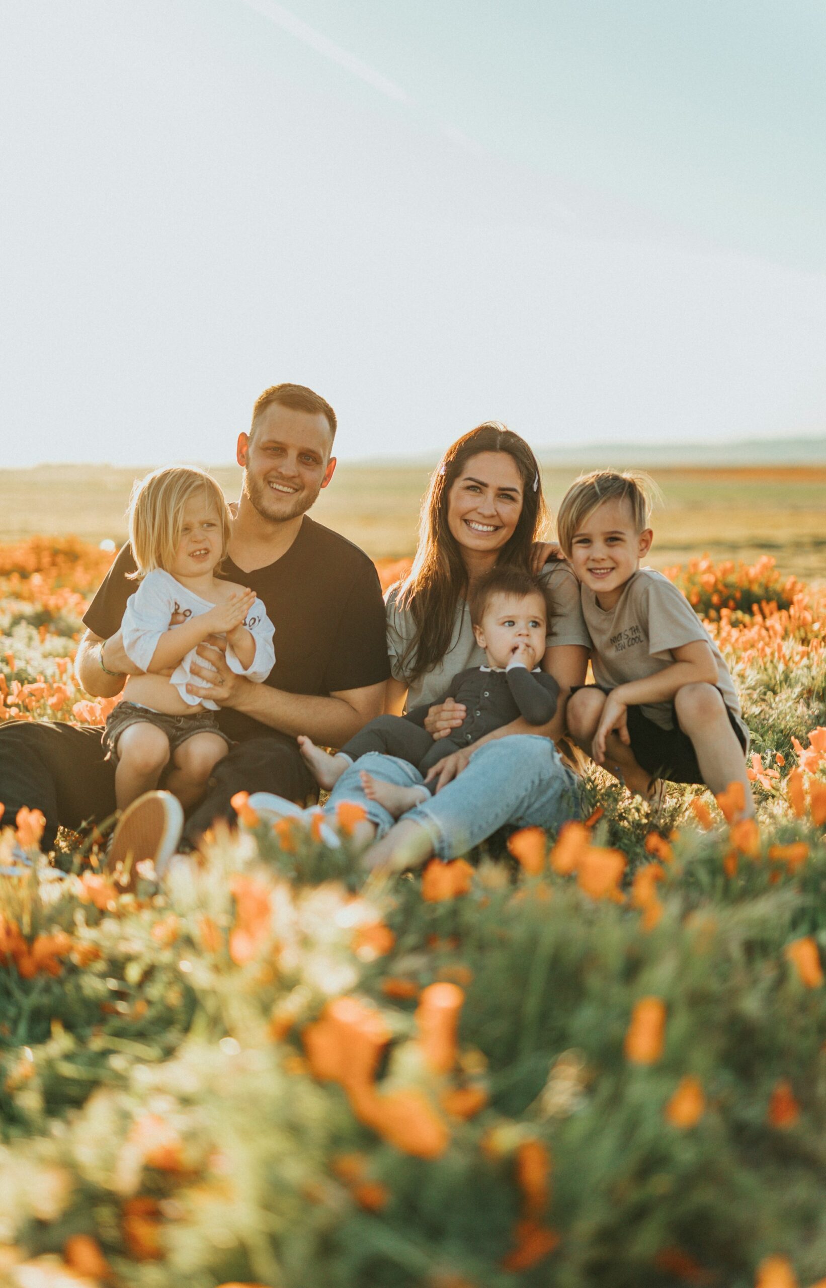 famille-heureuse-assisse-champs-fleurs