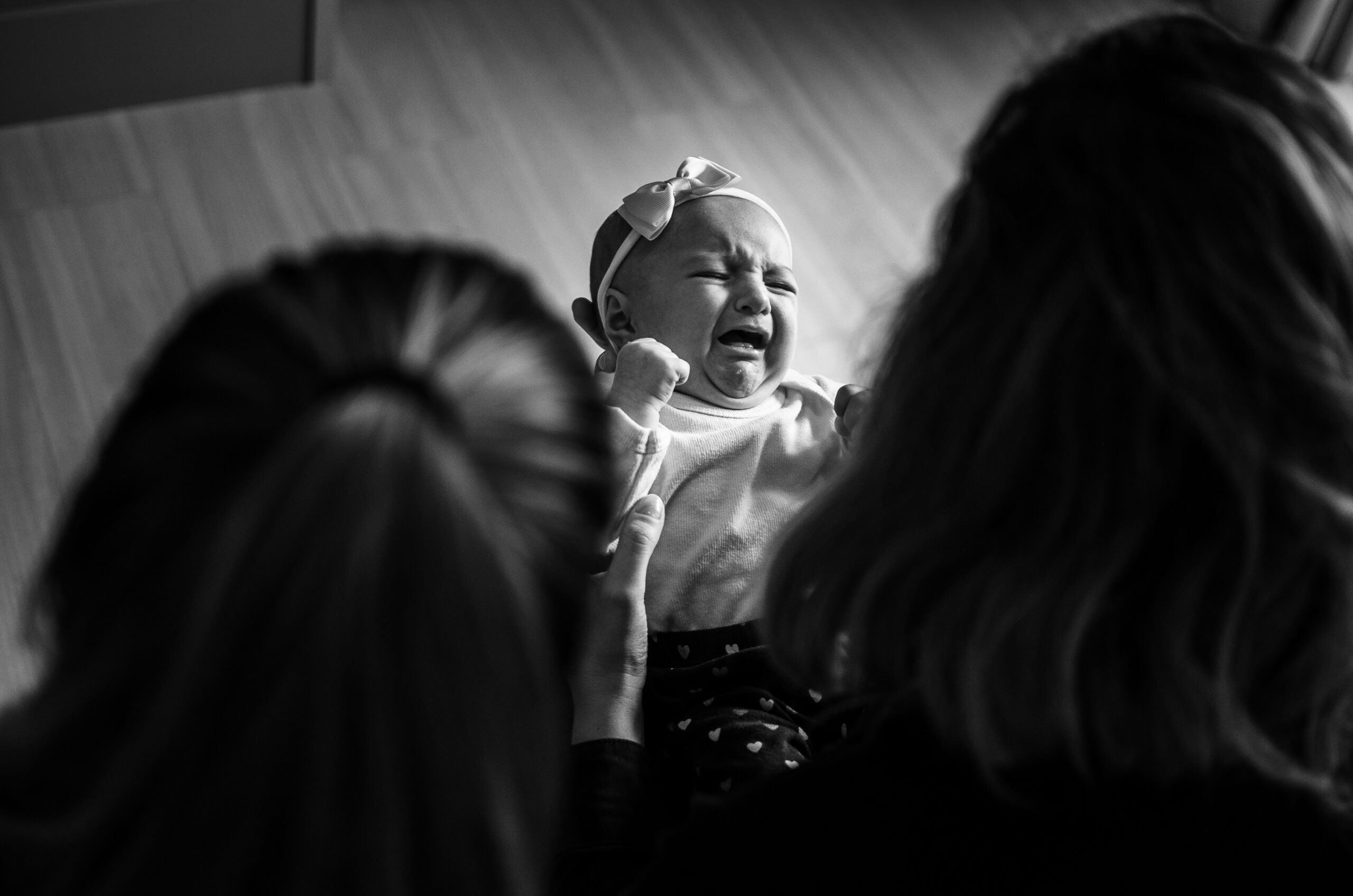 Bébé malade pleurant dans les bras de ses parents, montrant une détresse visible.