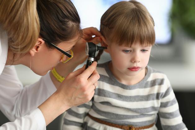 Une pédiatre examine l'oreille d'une jeune fille pour détecter une éventuelle otite.